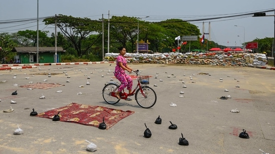 A woman cycles past makeshift barricades on a road in Yangon on March 13. Protests erupted across Myanmar on March 13 after posters surfaced on social media urging people to mark the death anniversary of Phone Maw, who was shot and killed by security forces in 1988 inside what was then known as the Rangoon Institute of Technology campus.(AFP)