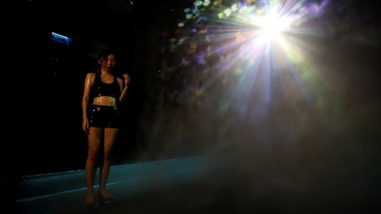 A staff of teamLab wearing a swimming suit takes shower next to a digital artwork combined with light, mist and sound during a demonstration of TikTok teamLab Reconnect, digital artwork combined with sauna, ahead of its opening to the public this month in Tokyo, Japan, March 13, 2021.  (REUTERS)