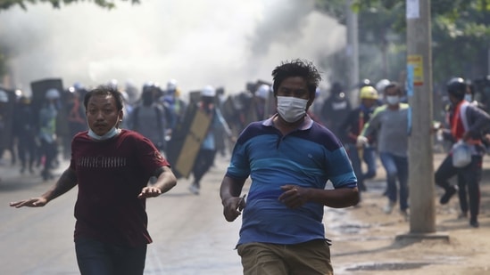Anti-coup protesters escape security forces firing tear gas in Mandalay, on March 13. According to the Assistance Association for Political Prisoners advocacy group, more than 70 people have been killed in Myanmar in widespread protests against a February 1 coup by the military.(AP)