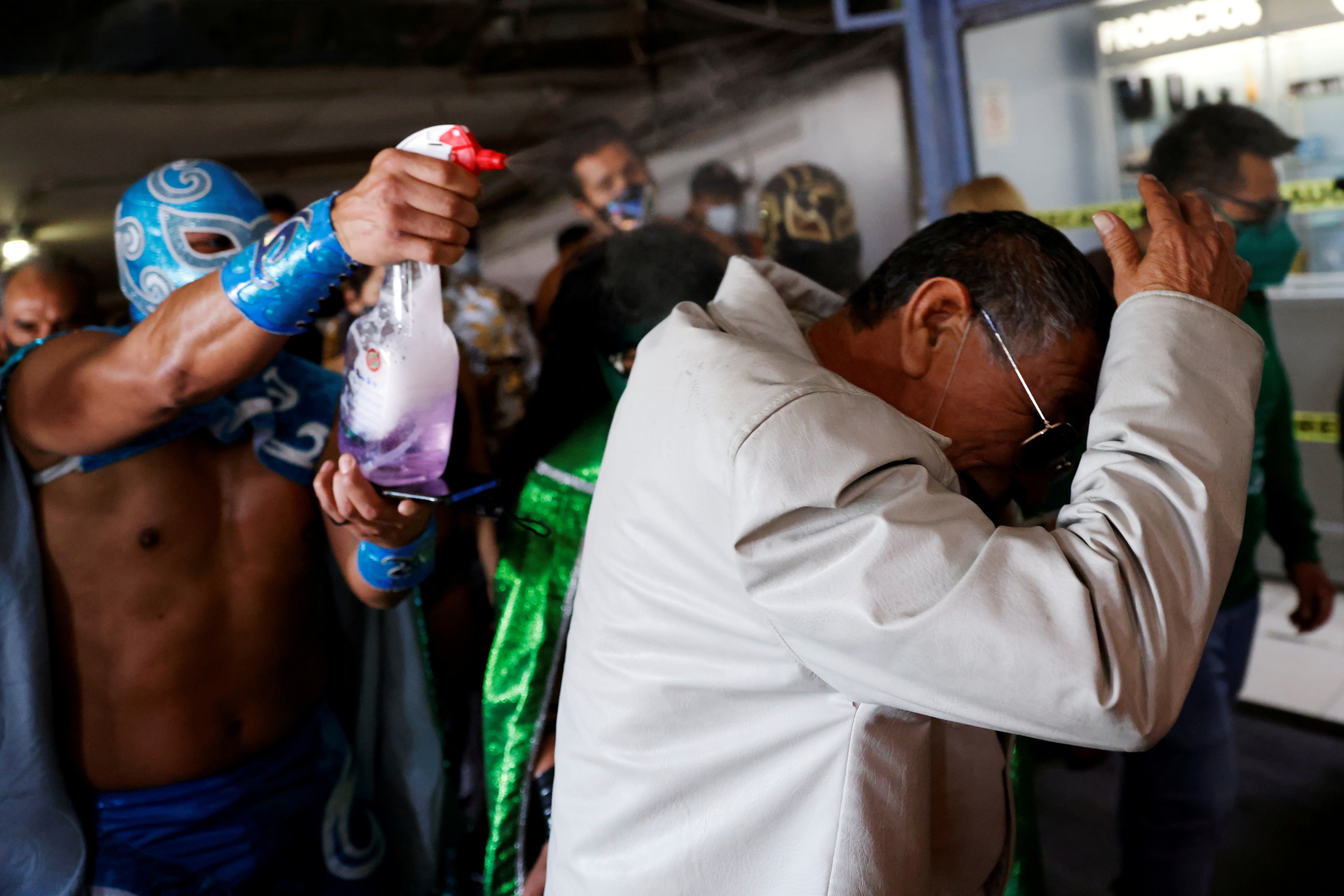 Lucha libre wrestler Ciclon Ramirez sprays water at a man as he and others encourage mask-less to wear masks as a measure of prevention against the continued coronavirus disease. (REUTERS)