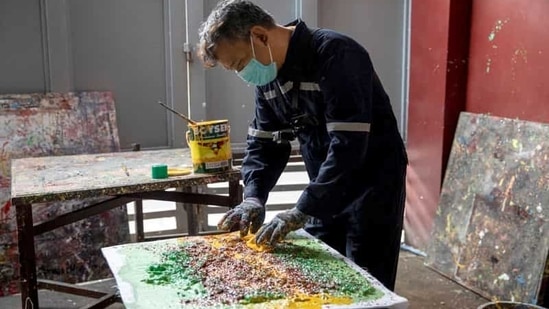 Filipino artist Gilbert Angeles incorporates expired paint and shredded plastic wrappers into a painting he is working on, at his studio in Plaridel, Bulacan province, Philippines, February 8, 2021. (REUTERS)