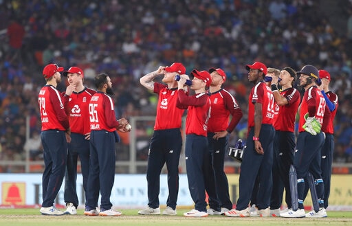 England players take a break as they await third umpire decision for the wicket of India's captain Virat Kohli during the second Twenty20 cricket match between India and England at Narendra Modi Stadium in Ahmedabad.