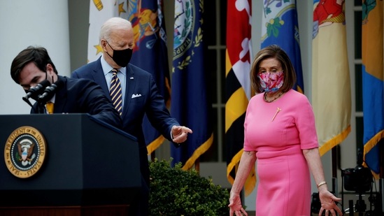 An aide sanitizes a podium as US President Joe Biden and House Speaker Nancy Pelosi (D-CA) arrive to speak about the $1.9 trillion "American Rescue Plan Act" during an event to celebrate the legislation in the Rose Garden at the White House in Washington, US, March 12, 2021. (REUTERS)