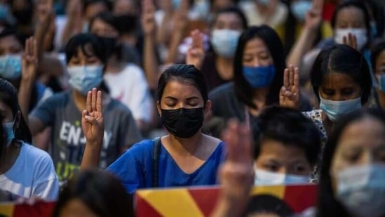 People flash a three-finger salute as they take part in an anti-coup night protest at Hiedan junction in Yangon, Myanmar, (Reuters)