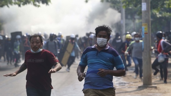 Anti-coup protesters escape security forces firing tear gas in Mandalay. (AP) Anti-coup protesters escape security forces firing tear gas in Mandalay. (AP)