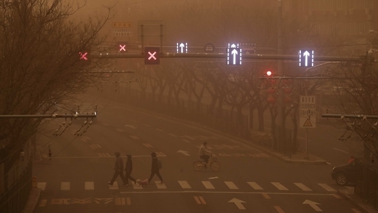 Commuters cross a street during the sandstorm in Beijing, on March 15. Under heavy skies, which draped buildings in an eerie glow, residents fretted over the health risks of a storm which compounded days of hazardous PM 2.5 pollution in Beijing.(Andy Wong / AP)
