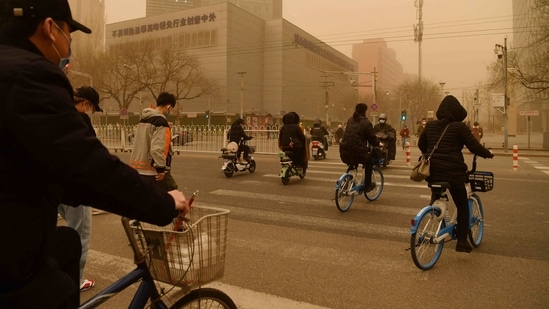 Cyclists cross a road during the sandstorm in Beijing, on March 15. Pan Xiaochuan, a Beijing-based environmental health expert, told AFP that the lack of recent rain or snow meant the ground was extra dry and made the sandstorm "very fierce."(Greg Baker / AFP)