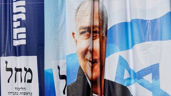Workers hang election campaign posters for Israel's Likud party bearing a portrait of its leader Prime Minister Benjamin Netanyahu on a billboard in the Israeli central city of Bnei Brak.(AFP)