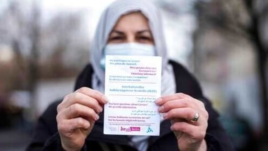 Aliye Tuerkyilmaz a member of a multilingual team of five street workers shows an information flyer as she poses for a photo in Berlin, Germany, Tuesday, March 9, 2021. Three times a week, Aliye Tuerkyilmaz hits the markets and busy shopping streets of Neukoelln, the German capital’s crowded immigrant neighborhood that’s studded with minarets, kebab stores and hookah lounges. The 48-year-old Turkish immigrant hands out flyers informing about the coronavirus pandemic and tries to connect with other immigrants in one of the four languages she speaks. Tuerkyilmaz belongs to an multilingual team, a group of five street workers trying to explain the dangers of COVID-19 to those who are often not reached through other efforts by the authorities. (AP Photo/Markus Schreiber)(AP)