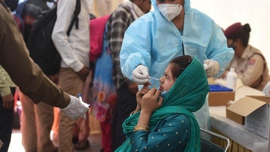 A health worker collects a swab sample for coronavirus testing at Anand Vihar Bus Terminal, in New Delhi, India.