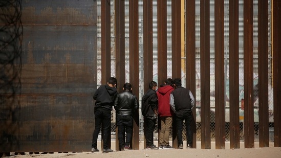 Migrants look through the border wall after crossing the Rio Bravo river, seen from Ciudad Juarez, Mexico, on March 14. The number of migrants being stopped at the US-Mexico border has been rising since last April, and the administration is still rapidly expelling most single adults and families under a public health order issued by President Donald Trump at the start of the Covid-19 pandemic, AP reported.(Jose Luis Gonzalez / REUTERS)