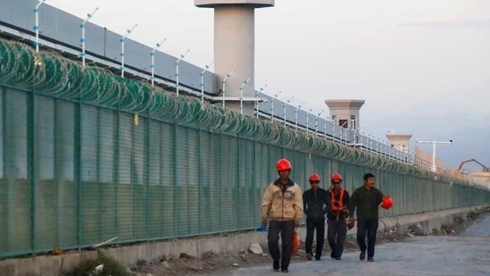 People walk by the perimeter fence of what is officially known as a vocational skills education centre in Dabancheng in Xinjiang Uighur Autonomous Region, China.(REUTERS/ FILE)