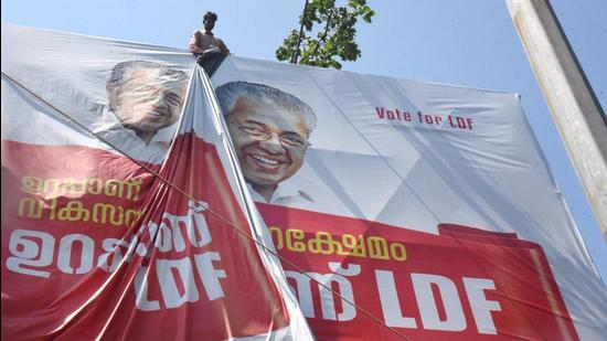 A worker puts up an election campaign banner of Kerala chief minister Pinarayi Vijayan, ahead of the assembly polls, in Kochi. (PTI)