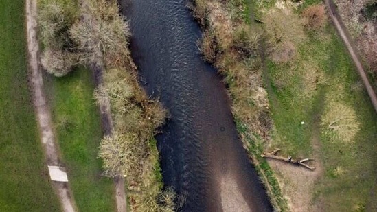 An aerial view shows people walking on a log along the bank of the River Tame near Denton, England on March 17. A University of Manchester report in 2018 found that the River Tame near Denton had 'the worst' level of micro-plastic pollution ever recorded anywhere in the world at that time.(Phil Noble / REUTERS)