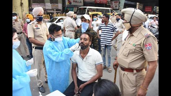 A health department staffer taking a sample from a mask violator for RT-PCR testing at Chaura Bazaar in Ludhiana on Saturday. (HT Photo) A health department staffer taking a sample from a mask violator for RT-PCR testing at Chaura Bazaar in Ludhiana on Saturday. (HT Photo)