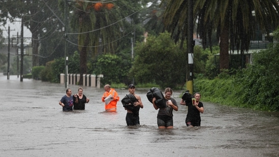 Residents wade through floodwaters with their belongings in Sydney on March 21. Another 1,000 people were asked to evacuate on March 21, after Berejiklian said that some 4,000 people may be asked to leave their houses, Reuters reported.(Loren Elliott / REUTERS)