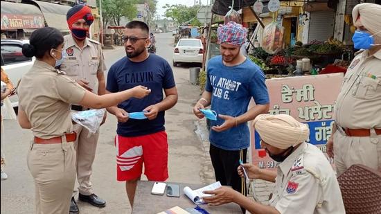 Hathur station house officer, sub-inspector Arshpreet Kaur along with the police party issuing challans to residents roaming around without masks in Ludhiana on Sunday. (HT PHOTO) Hathur station house officer, sub-inspector Arshpreet Kaur along with the police party issuing challans to residents roaming around without masks in Ludhiana on Sunday. (HT PHOTO)