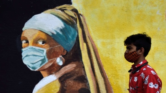 A boy walks past a mural spreading awareness about Covid-19 depicting the Girl With A Pearl Earring wearing a face mask, at Khar in Mumbai, on March 19. India registered over one lakh cases in just three days. On March 20, India saw 40,953 new cases, 39,726 new cases were registered on March 19 and 35,871 cases on March 18, HT reported.(Satish Bate / HT Photo)