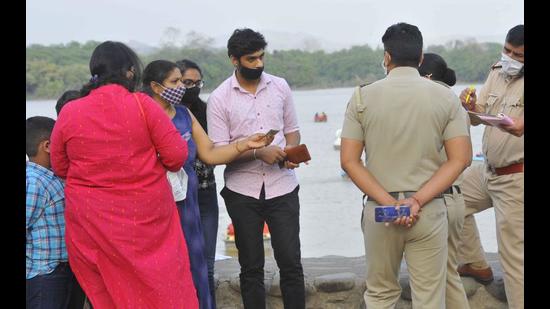 Police personnel challaning people found loitering without masks at Sukhna Lake in Chandigarh on Sunday. (Keshav Singh/HT) Police personnel challaning people found loitering without masks at Sukhna Lake in Chandigarh on Sunday. (Keshav Singh/HT)
