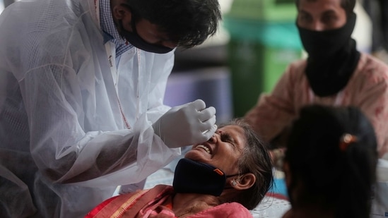 A health worker collects nasal swab of a passenger for Covid-19 test at a long distance train station in Mumbai on March 21, 2021. (AP Photo) A health worker collects nasal swab of a passenger for Covid-19 test at a long distance train station in Mumbai on March 21, 2021. (AP Photo)