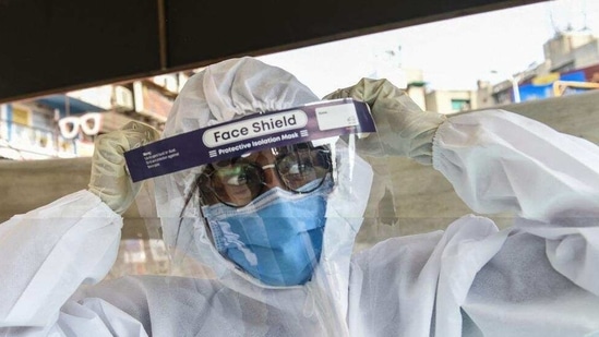 A health worker wears a Personal Protective Equipment (PPE) suit before collecting swab samples from people to test for the Covid-19