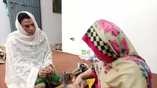 Rani Khan, a transgender woman who teaches the Koran at Pakistan's first transgender only madrasa or a religious school, looks at one of her students during a tailoring lesson in Islamabad, Pakistan.(Reuters)