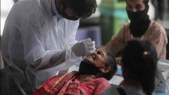 A health worker collects nasal swab of a passenger for Covid-19 test at a long distance train station in Mumbai, on Sunday, March 21. (AP)