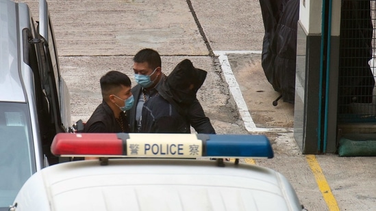 One of the eight Hong Kong pro-democracy activists, with black hood, is escorted by police officers after arriving at a police station in Hong Kong. (AP) One of the eight Hong Kong pro-democracy activists, with black hood, is escorted by police officers after arriving at a police station in Hong Kong. (AP)