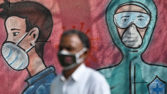 A pedestrian walks past a wall mural depicting frontline Covid-19 coronavirus warriors wearing face masks along a road.(AFP) A pedestrian walks past a wall mural depicting frontline Covid-19 coronavirus warriors wearing face masks along a road.(AFP)