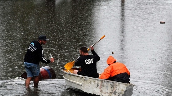 Residents commute on a boat in a flooded residential area near Windsor on March 22, 2021, as torrential downpours lashed Australia's east forcing thousands to flee the worst flooding in decades.(AFP)