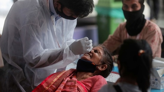 A health worker collects nasal swab of a passenger for Covid-19 test. (AP Photo) A health worker collects nasal swab of a passenger for Covid-19 test. (AP Photo)