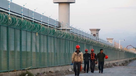 People walk by the perimeter fence of what is officially known as a vocational skills education centre in Dabancheng in Xinjiang Uighur Autonomous Region, China.(REUTERS/ FILE)