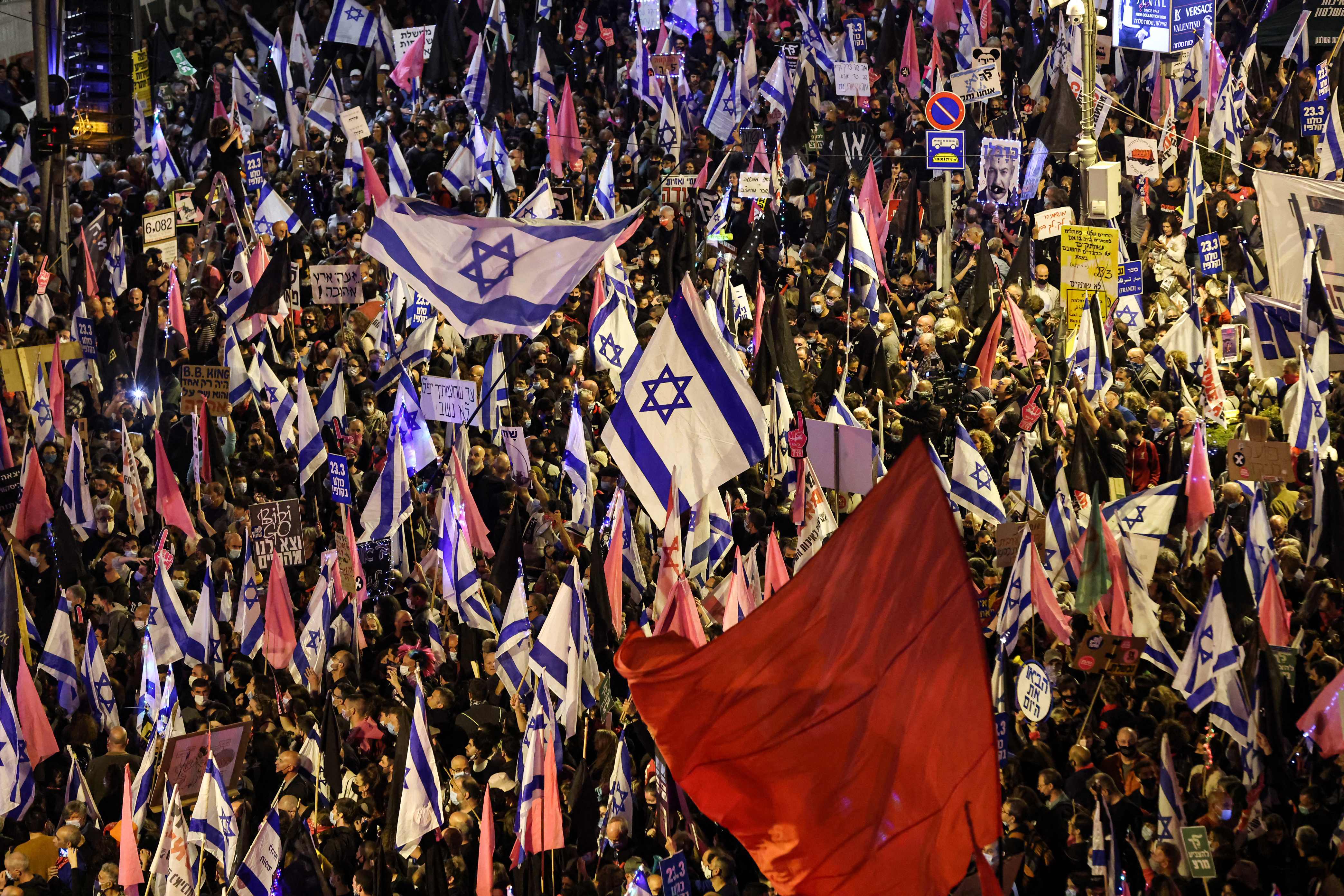 Protesters gather with Israeli and coloured red and pink flags during an anti-government demonstration near the Israeli prime minister's residence in Jerusalem. (AFP) Protesters gather with Israeli and coloured red and pink flags during an anti-government demonstration near the Israeli prime minister's residence in Jerusalem. (AFP)