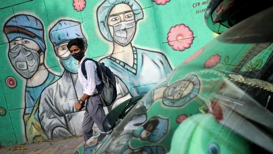A student walks past a wall with the graffiti of frontline workers wearing face masks, in New Delhi on Monday. (ANI Photo) A student walks past a wall with the graffiti of frontline workers wearing face masks, in New Delhi on Monday. (ANI Photo)