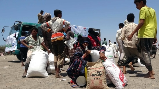 People displaced by conflict receive food aid donated by a Kuwaiti charity organisation in the village of al-Haima in the Khokha district of Yemen's war-ravaged western province of Hodeida, on March 20, 2021. (AFP) People displaced by conflict receive food aid donated by a Kuwaiti charity organisation in the village of al-Haima in the Khokha district of Yemen's war-ravaged western province of Hodeida, on March 20, 2021. (AFP)