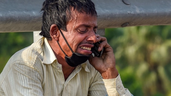 A migrant labourer gets emotional while talking to a relative over his mobile phone at Nizamuddin Bridge, May 11, 2020. (PTI)