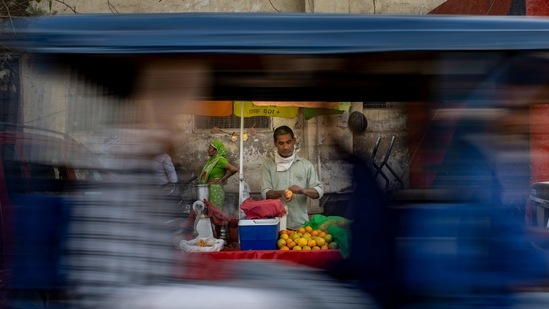 Ganesh Chaurasia, 42, a roadside juice vendor, is seen through a passing rickshaw as he waits for customers in New Delhi on March 16. Chaurasia told AP the lockdown plummeted his income and pushed his family, that is still struggling to make their ends meet, into economic despair. Street vendors like Chaurasia represent 4% of the urban workforce across India, AP reported.(Altaf Qadri/AP)