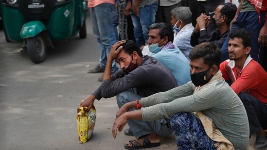 Nirbhay Yadav (wearing checked scarf) and his son Lovelesh Yadav waiting for work in New Delhi on March 18. The two travelled 600 kilometers on foot, braving scorching sun and hours of thirst and hunger. When they finally reached home, villagers didn't allow them to enter the village because of fears of coronavirus transmission and were sent to a 14-day quarantine(Manish Swarup/AP)