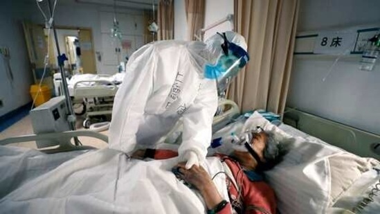 An elderly woman with Covid-19 is comforted by a doctor at a hospital in Wuhan, China in a scene from the documentary "76 Days."(via AP)