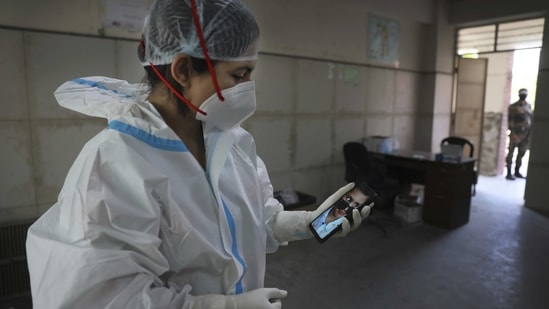 Health worker Kavita Sherawat, 30, shows a photograph of her son Parakhshit before proceeding to take samples to test for Covid-19, in New Delhi on March 18. Despite dutifully wearing masks and always washing her hands, Sherawat got infected, as did her husband, parents and in-laws. While doctors and nurses were cheered as heroes during the lockdown, people avoided her, fearing infection.(Manish Swarup/AP)