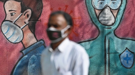 A pedestrian walks past a wall mural depicting frontline Covid-19 coronavirus warriors wearing face masks along a road. (AFP) A pedestrian walks past a wall mural depicting frontline Covid-19 coronavirus warriors wearing face masks along a road. (AFP)