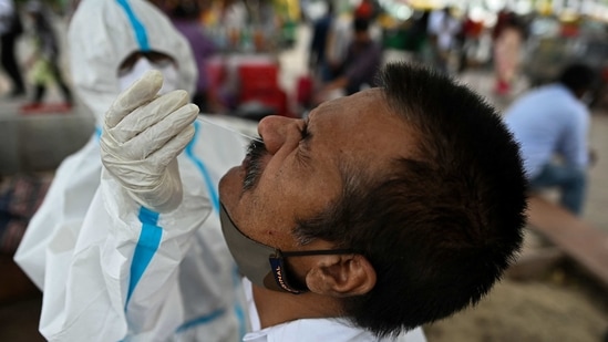 A health worker wearing protective gear collects a swab sample from a man for the Covid-19 coronavirus Rapid Antigen Test (RAT) along the roadside in New Delhi. A health worker wearing protective gear collects a swab sample from a man for the Covid-19 coronavirus Rapid Antigen Test (RAT) along the roadside in New Delhi.