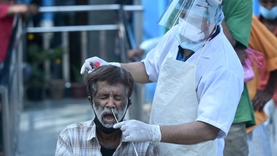 A health worker collects swab sample from a person for Covid-19 test, near Kashmere Gate in New Delhi.(PTI)