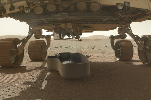 This photo made available by NASA shows the released debris shield, center, for the Ingenuity helicopter, dropped on the surface of Mars from the bottom of the Perseverance rover. (AP) This photo made available by NASA shows the released debris shield, center, for the Ingenuity helicopter, dropped on the surface of Mars from the bottom of the Perseverance rover. (AP)