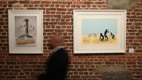 An art handler walks past works by street artist Banksy, as preparations take place for the exhibition "Banksy, The Brussels Show", that will present the artist's most representative works, in Brussels, Belgium March 24, 2021. REUTERS/Yves Herman NO RESALES. NO ARCHIVES(REUTERS)