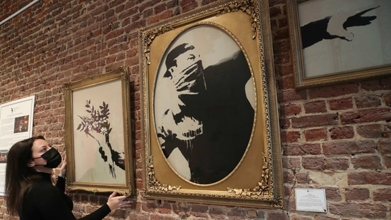An art handler shows to reporters work "Love Is In The Air" by street artist Banksy, as preparations take place for the exhibition "Banksy,(REUTERS)