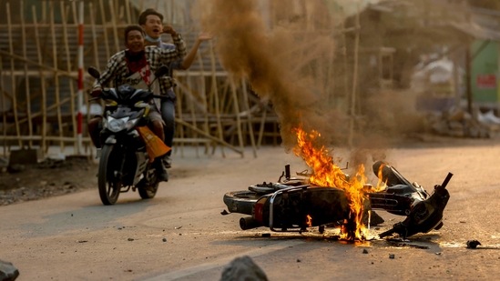 Two men on a motorbike alert people and anti coup protesters as armed security forces arrive to crack down on a demonstration in Mandalay, Myanmar, (AP) Two men on a motorbike alert people and anti coup protesters as armed security forces arrive to crack down on a demonstration in Mandalay, Myanmar, (AP)