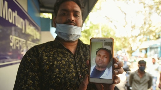 A relative showing a picture of Lokesh who died inside a manhole while cleaning the septic tank at Grand Emperor Banquet Hall, in Ghazipur, New Delhi, India, on Friday, March 26, 2021. Two people dies in the incident. (Photo by Amal KS / Hindustan Times)