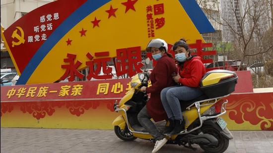 Residents wearing masks pass by government propaganda with slogans some of which read "Forever follow the Party" and "China's Ethnicities One Family" in the city of Aksu in western China's Xinjiang region. (AP) Residents wearing masks pass by government propaganda with slogans some of which read "Forever follow the Party" and "China's Ethnicities One Family" in the city of Aksu in western China's Xinjiang region. (AP)
