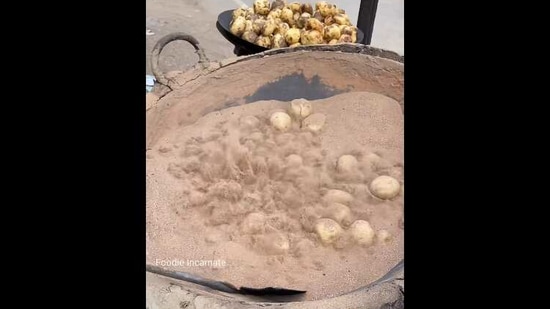 The image shows the potatoes in a large sand-filled wok.(Facebook/@Foodie_incarnate)